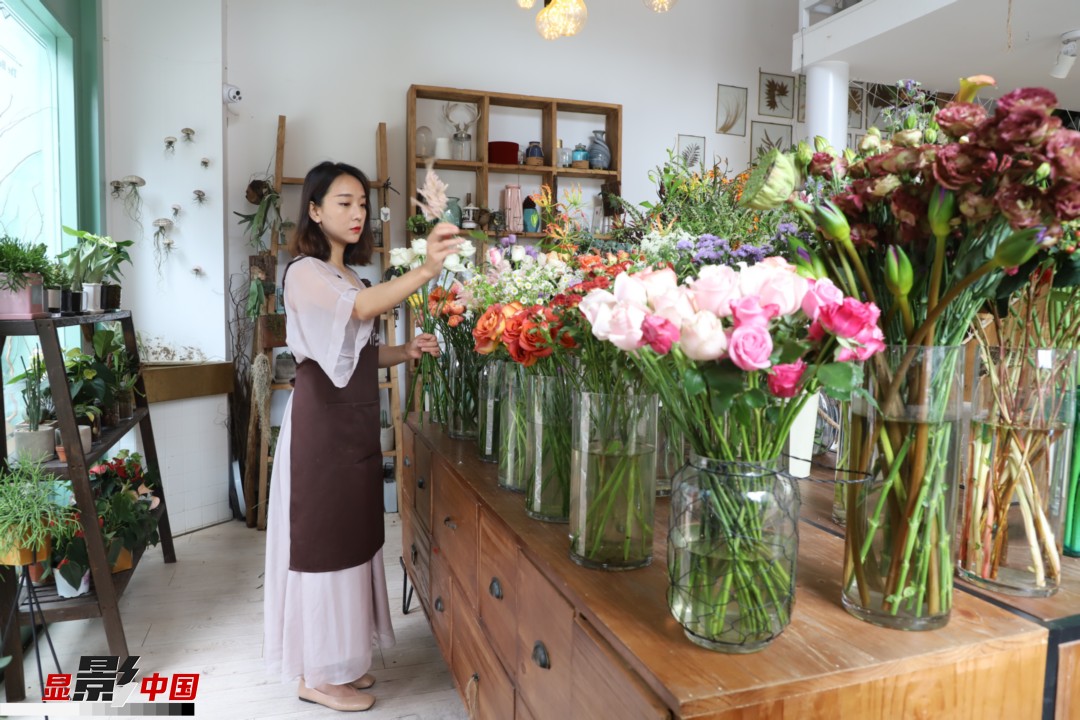 王黎媛是一名河南姑娘，在昆明念完大學(xué)后，就再也舍不下春城的藍(lán)天陽光、青山碧水，更舍不下這里的四時繁花，于是就干脆留了下來，成了一名媒體人。2017年的時候又毅然辭去工作，創(chuàng)業(yè)開起了花店，成了都市里的一名“花房姑娘”。圖為王黎媛在自己的花店中整理鮮花。新華網(wǎng) 周亞平/攝 念新洪/文